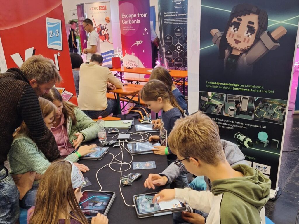 Am Qookies-Stand im Science Playground der Spielwiesn in Augsburg spielen Kinder und Erwachsene die Demoversion von Qookies.